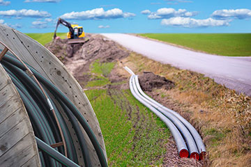 Construction crew installing fiber optic cable along a road.