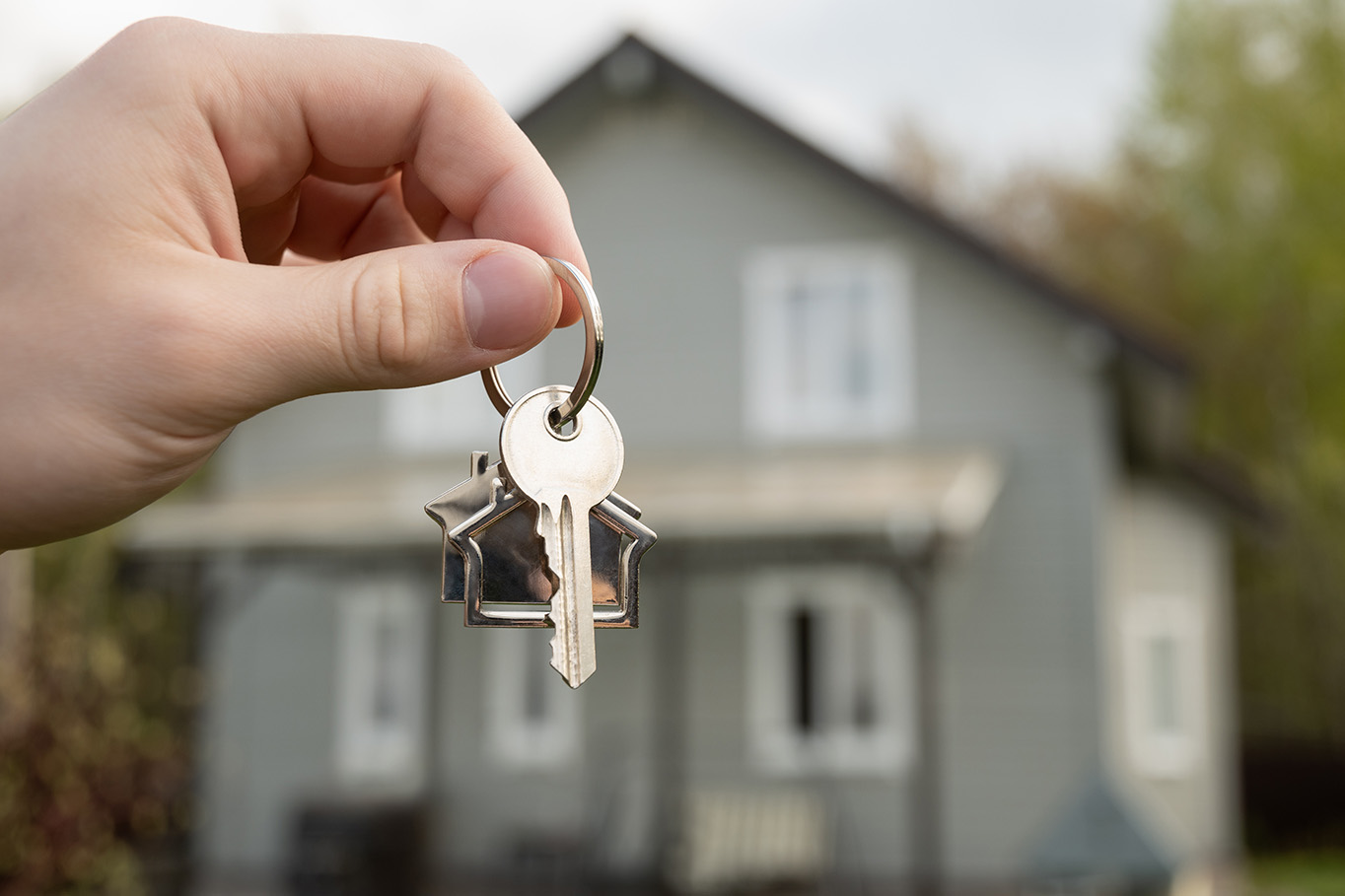 Someone holding a set of keys in front of a home.