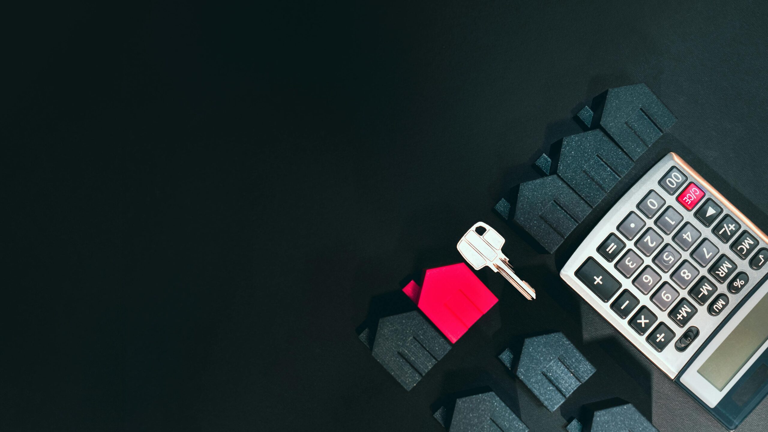 A calculator and key on a desk.